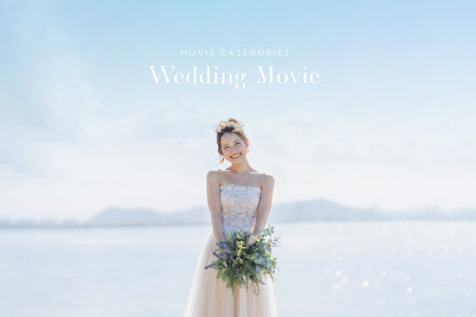 美しいストラップレスのウェディングドレスを着た喜びに満ちた花嫁が、ラベンダーとグリーンのブーケを持って温かく微笑んでいます。彼女は明るい青空の下、大きな水辺の前に立っています。上部には『ウェディングムービー』と『映画カテゴリー』というテキストが表示されています。