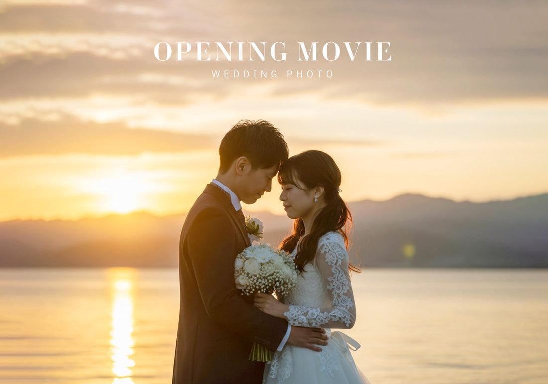 夕暮れ時の琵琶湖畔での結婚式ムービー用のオープニングムービーフォトを撮影中。ブーケを持った白いレースのドレスを着た新郎と、スーツを着た新郎が抱き合っています。